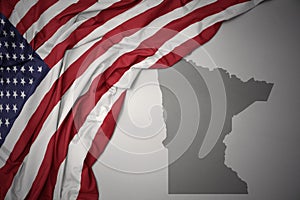 Waving national flag of united states of america on a gray minnesota state map background.