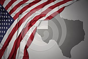 Waving national flag of united states of america on a gray texas state map background.