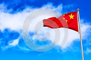 Waving red national flag of China against blue sky background