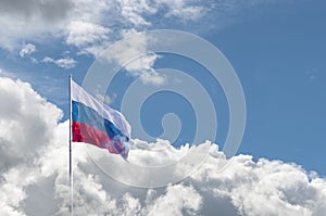 Waving Russian flag against a blue sky with clouds and empty space for text. Room for text. Abstract collage.