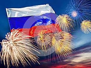 Waving russian flag against sunset sky with colorful exploding fireworks. Victory or independence day concept
