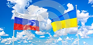 Waving Russian and Ukraine flags against blue sky with clouds