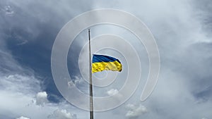 Waving Ukrainian half-mast flag against a beautiful sky with clouds.