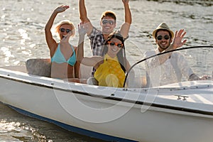 Waving young people sitting in motorboat
