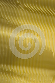 Wavy contours in spreadable margarine. Vertical food texture image