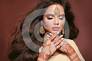 Wavy hair. Portrait of beautiful woman with indian jewelry. Young brunette model with Traditional Indian golden bijouterie set.