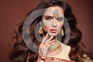Wavy hair. Portrait of beautiful woman with indian jewelry. Young brunette model with Traditional Indian golden bijouterie set.