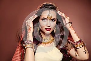 Wavy hair. Portrait of beautiful woman with indian jewelry. Young brunette model with Traditional Indian golden bijouterie set.