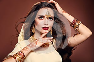 Wavy hair. Portrait of beautiful woman with indian jewelry. Young brunette model with Traditional Indian golden bijouterie set.