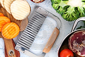 wavy knife for vegetables. Carrot slices and potatoes on a cutting board. Saucepan, Onions, broccoli, tomatoes and parsley top