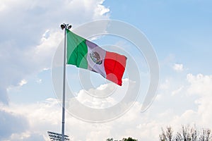 Wavy Mexican flag with a cloudy sky as background