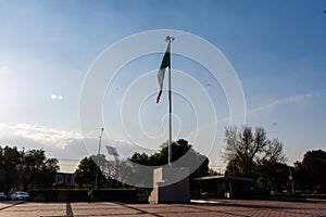 Wavy Mexican flag and public square in the morning