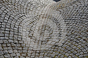 Wavy paving of cubes in the form of a woman bust. creates a gutter saddle between two hills. the bumpy steep paving copies the ter