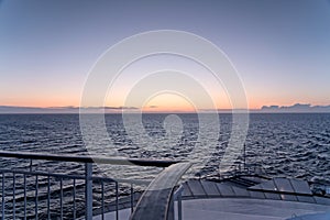 Wavy sea and a beautiful orange and blue evening sky on the aft deck of the cruise ship