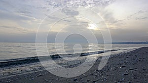 Wavy seascape view from the beach with pebbles and seashells on it.