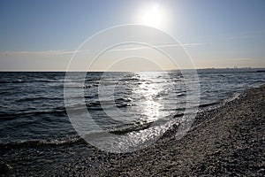 Wavy seascape view from the beach with pebbles and seashells on it.