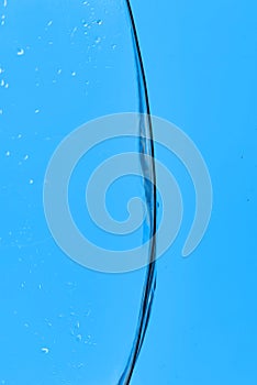 Wavy transparent water on blue background with droplets.