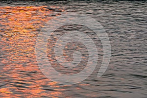 Wavy water surface with glittering orange sun light. 7