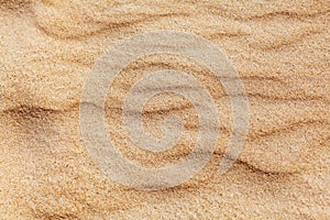 Wavy yellow sand texture background, sandy waves pattern, sand grains, rippled dry sand surface top view, desert dune