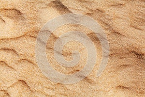 Wavy yellow sand texture background, sandy waves pattern, sand grains, rippled dry sand surface top view, desert dune