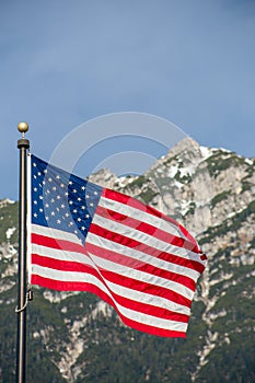 Wawing American flag against mountains of rocks and blue sky