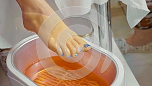 Wax bath for feet at beauty spa salon, close-up.