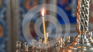 Wax burning candle in an orthodox church on the icon background