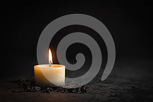 A wax candle is burning on a dark background. Flame of one candle at night close-up.