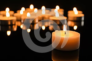 Wax candle burning on table in darkness