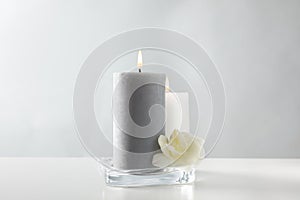 Wax candles and flower in glass holder on table against background