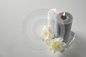 Wax candles and flowers in glass holder on table. Space for text