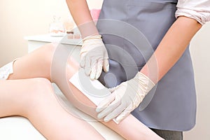 Wax depilation of legs, depilation of a young woman