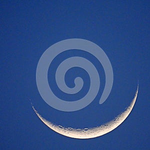 Waxing crescent moon in afternoon twilight blue sky