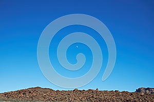 Waxing crescent moon during the day on the blue sky on volcanoTeide