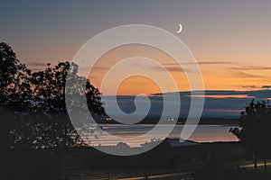 Waxing crescent moon over the sea at Sandwich bay during the golden hour sunset