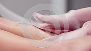 Waxing master depilating woman's legs using waxing strips