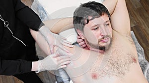 Waxing procedure - bearded man depilating hairs from his armpits in the salon
