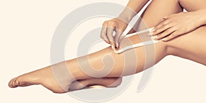 Waxing woman leg with wax strip at beauty spa. Close-up waxing woman leg in spa. Well-groomed woman legs after