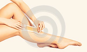 Waxing woman leg with wax strip at beauty spa. Closeup waxing woman leg in spa. Beautician waxing female legs in spa