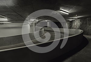 Way down to underground car parking. Perspective view of Curving shaped ramp of the basement made of concrete