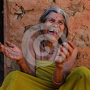 Laughing old nepalese woman with her back agaist an earthen wall