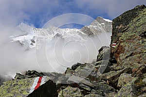 Way marking signs with snowy alp tops in the background