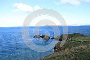 Way to Carrick-a-Rede Rope Bridge - Island in blue ocean with light blue sky - Northern Ireland tourism