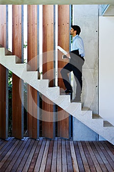 On the way to his office. A young businessman walking up the stairs.