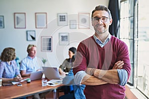 The only way to lead is with confidence. Portrait of a confident mature man with his team in the background of a modern