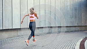 On the way to success.Back view of young disabled woman with leg prosthesis in comfortable sports clothing is running