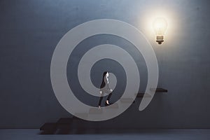 Way to success and creative idea concept with woman climbing the stairs to big illuminated light bulb on dark grey wall