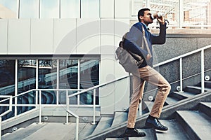 The way to success is paved with coffee. a young businessman drinking coffee while walking through the city.