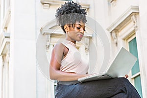 Way to Success. Young African American woman with afro hairstyle wearing sleeveless light color top, sitting by vintage office