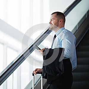 On the way to where the money is. a businessman traveling down an escalator in an airport.